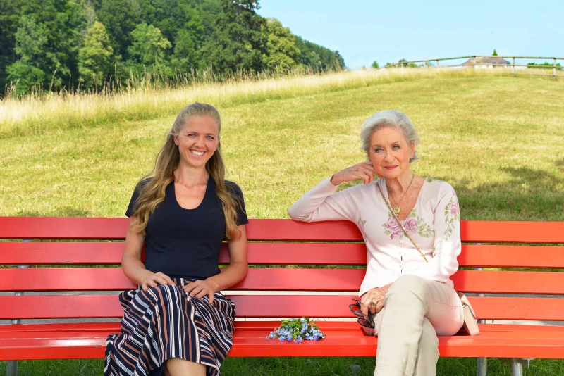 Campagne de dons : « Faire le bien, ça dure ». Deux femmes sont assises sur un banc rouge.